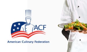 A chef in a white uniform with a plate of greens