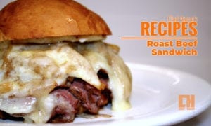 Roast beef sandwich on a white plate with orange letters overlayed